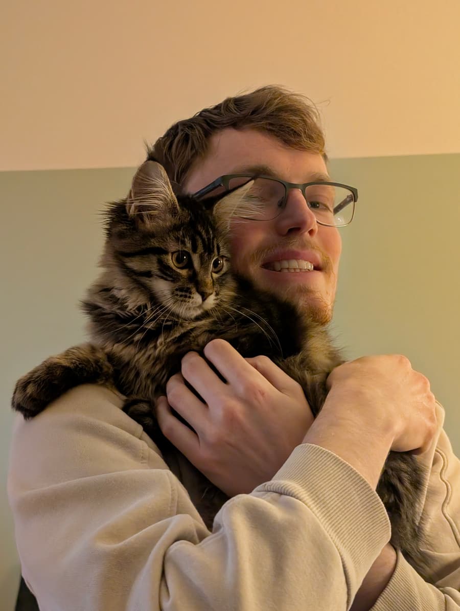 Aaron cuddling a fluffy tabby kitten