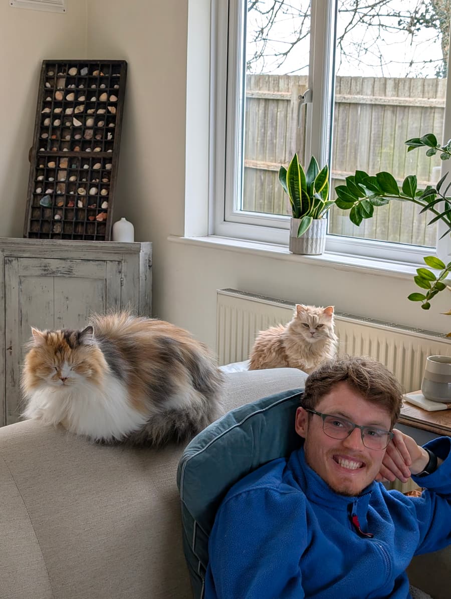 Aaron at home with two fluffy cats