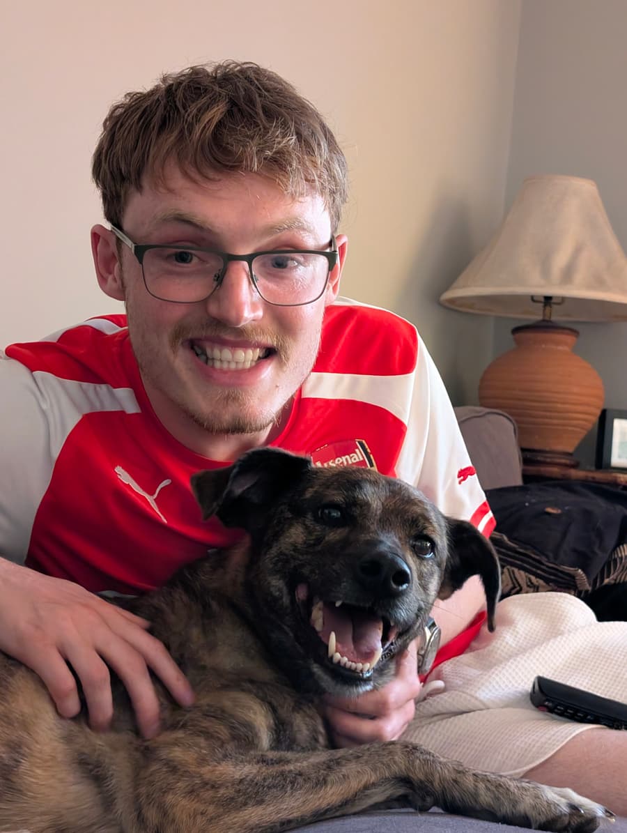 Aaron smiling with a happy brindle dog
